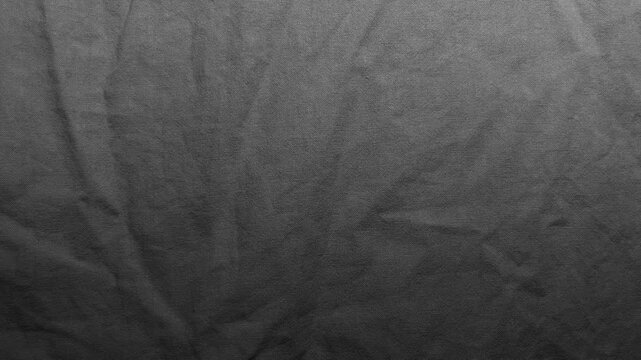 dark gray textured fabric background shows soft creases on fine woven linen material creating subtle monochrome shadows