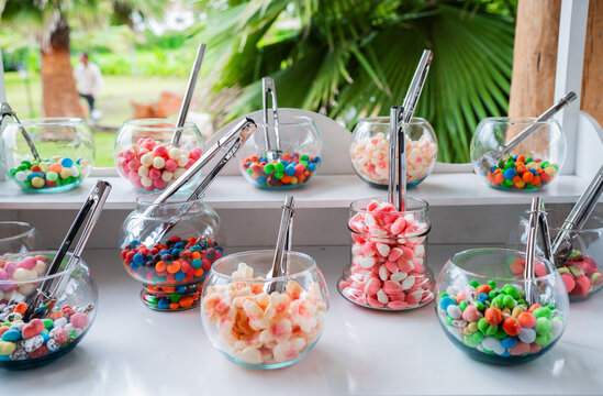 Mesa de dulces con frascos de vidrio y variedad de caramelos de colores para boda, fiesta o evento