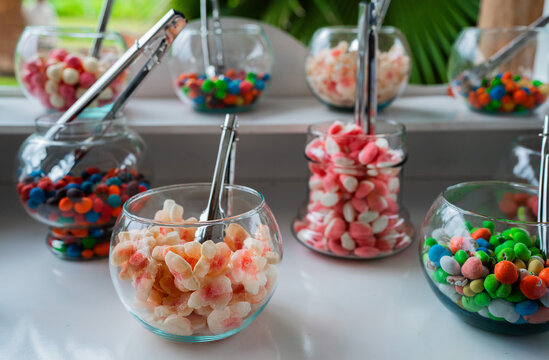 Frascos de vidrio con surtido de caramelos y golosinas en mesa de dulces para bodas y celebraciones