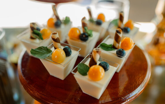 Postres gourmet individuales con frutas frescas y barquillos en mesa de celebraci&oacute;n elegante