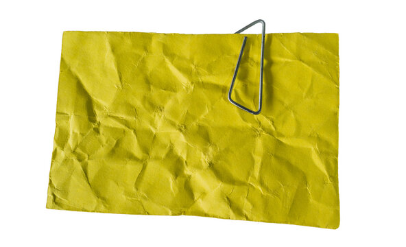 Hoja de papel amarillo arrugada con clip met&aacute;lico aislada sobre fondo negro, concepto de organizaci&oacute;n y recordatorios