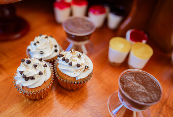 Cupcakes gourmet y postres variados sobre mesa de madera en elegante mesa dulce para celebración © Manuela