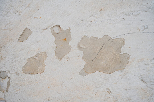 Textura de pared blanca con pintura descascarada y revoque deteriorado sobre superficie de cemento