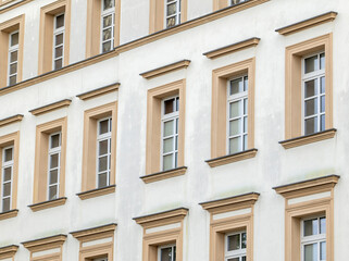 Obraz premium European tenement facade with repeated beige framed windows, angled closeup of apartment or hotel exterior, city real estate, accommodation, rental property and architecture pattern concept, no people