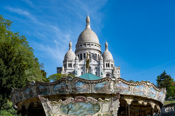 Fototapeta premium Spring day in Montmartre with cobblestone streets, whitewashed historic houses, and Sacré-Cœur Basilica towering overhead. Parisian artistic neighborhood, France