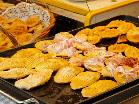 Traditional Polish oscypek smoked cheese grilling with bacon on hot electric griddle, closeup of golden street food market stall snack, regional mountain cuisine and winter festival menu concept