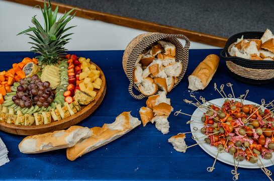 Mesa de buffet con tabla de frutas frescas, pan artesanal y aperitivos de embutidos para eventos