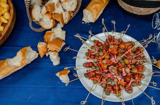 Tabla de aperitivos con brochetas de aceitunas, embutidos y tomates cherry acompa&ntilde;adas de pan artesanal