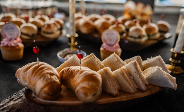 Mesa de catering con variedad de bocadillos, s&aacute;ndwiches y aperitivos gourmet para celebraci&oacute;n o evento