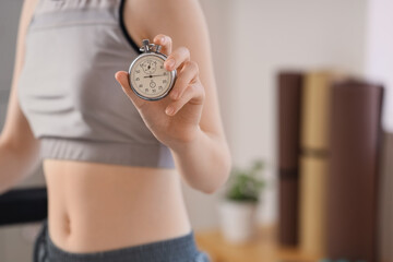 Obraz premium Woman in athletic wear holding a stopwatch, fitness and exercise timing, workout progress and personal training