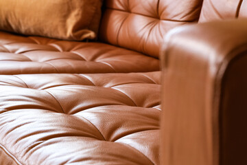 Obraz premium Brown leather sofa with tufted cushions and a soft pillow, comfortable home furniture detail, this furniture piece offers a warm and inviting atmosphere