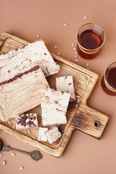 Pieces of tasty marble halva and glasses with Turkish tea on brown background