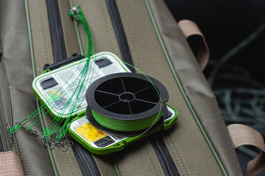 Fishing tackle box with braided fishing line spool and wire leaders on a gear bag. Freshwater angling equipment for fishing preparation, outdoor recreation and sport fishing.