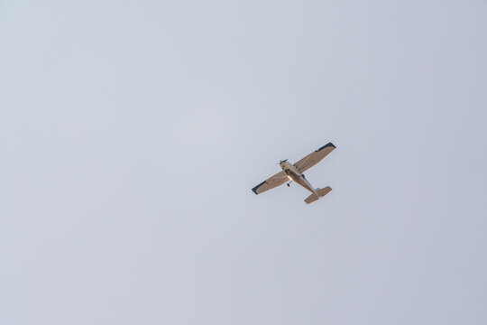Small ultralight airplane with overhead wing and single propeller flying in sunset sky.