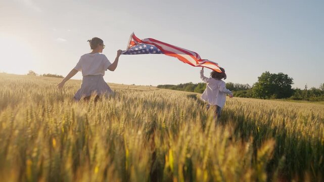 Mother and young son run through wheat field carrying United States flag during sunset. Golden hour, family values and patriotic spirit symbolize freedom, national pride and American heritage.