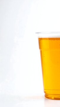 Clear Plastic Cup Filled with Golden Amber Liquid Against White Background