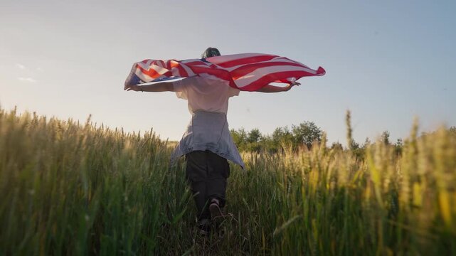 Happy woman runs in open field, holding the United States flag as it waves in breeze. Independence Day, American values, military support, political activism, national heritage. 