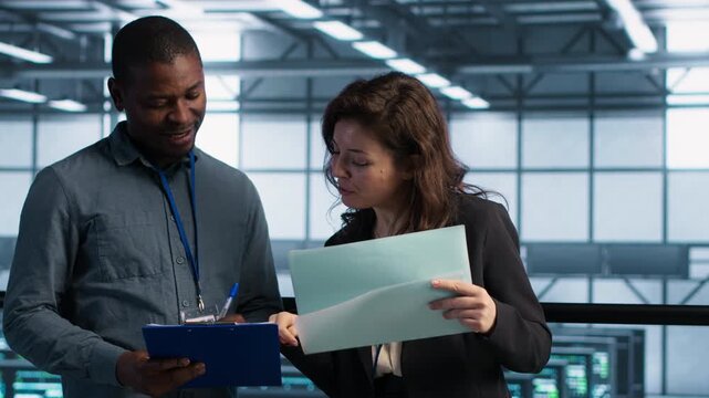 IT professionals review technical documentation in a server room, checking reports, maintenance files and system diagnostics for reliable operations.