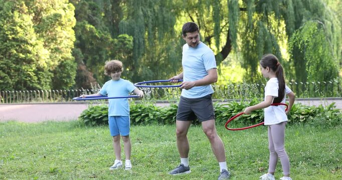 Father and his kids exercising with hula hoops in park