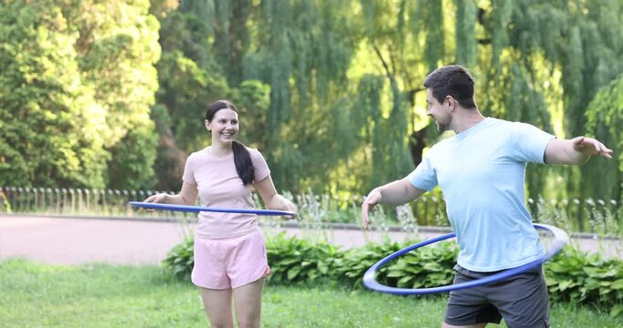 Couple exercising with hula hoops in park