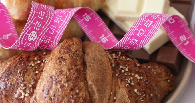 Measuring tape and desserts on table, spinning. Closeup view