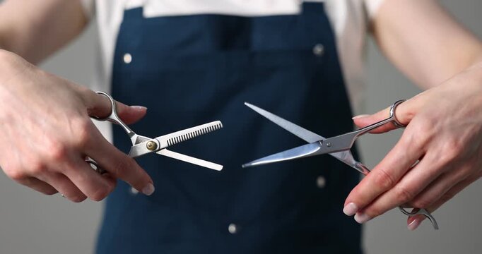 Professional hairdresser with scissors on grey background, closeup
