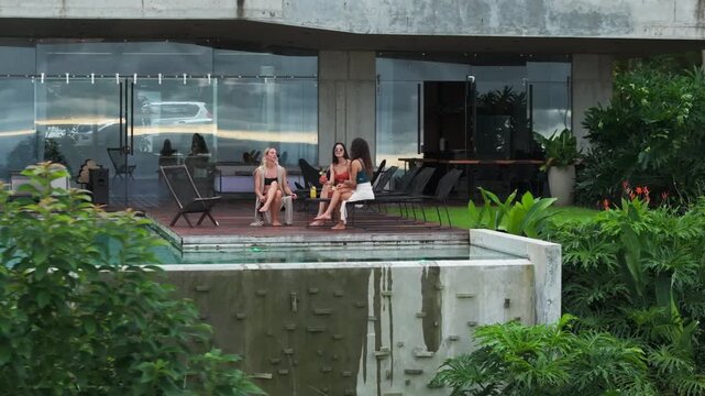 In a delightful and relaxing moment by the shimmering pool, three girls are fully immersed in the stunning beauty of a lavish Costa Rican residence, beautifully nestled among lush greenery