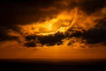 Fototapeta premium Dramatic sunset clouds over the ocean with golden light rays breaking through