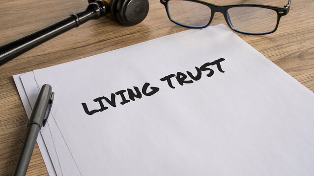 Living Trust legal document on wooden desk with gavel and glasses