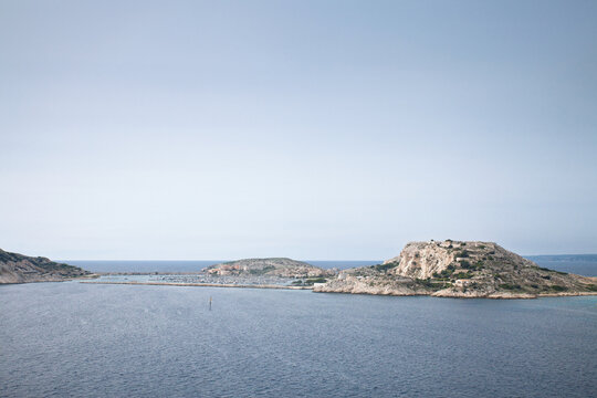 Panoramic view of Port Frioul on Ile Ratonneau in the Iles du Frioul, with marina waters, rocky coastline, island fortifications, and the Mediterranean Sea in Marseille, France.