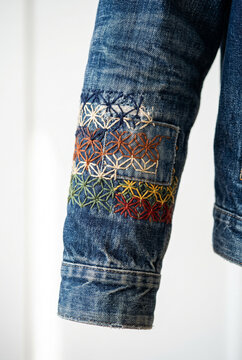 Close-up of denim jacket sleeve with colorful sashiko embroidery patch detail