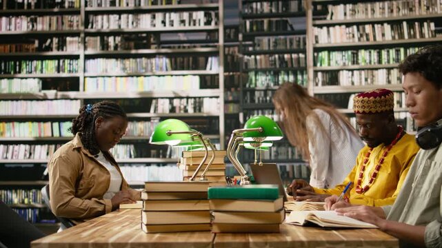 Adult learner in traditional yellow clothing sitting at library study desk during computer class, mature student in african robe suggesting digital education and study practice, for coursework.