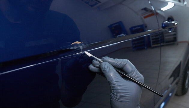 Automotive Technician Measuring Car Body Panel Dent With Paintless Dent Repair Inspection Tool