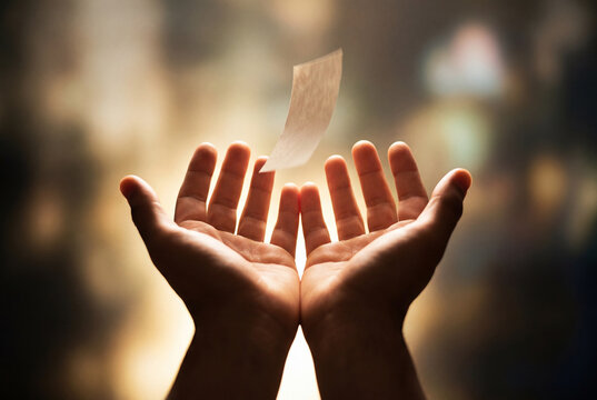 Cupped hands releasing paper with the word forgive into the air