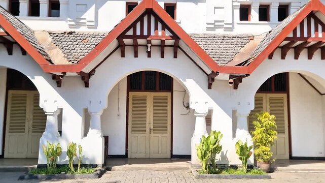 Madiun, 8 July, 2026: Historic Dutch colonial architecture building in Indonesia with sturdy white facade, red tile roof, and classic arched louvered doors, built in 1912.