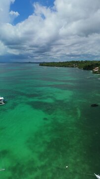 Vertical drone flies over anchored outrigger boats and ascends above shallow turquoise water along Panglao, Bohol