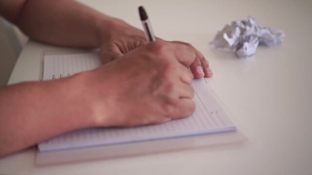 Hand writing text in spiral notepad on white table an then make mistake. Close-up shot, business and work concept, office productivity and note-taking.