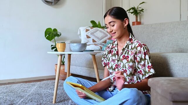 Young woman drawing with stylus on a digital tablet at home