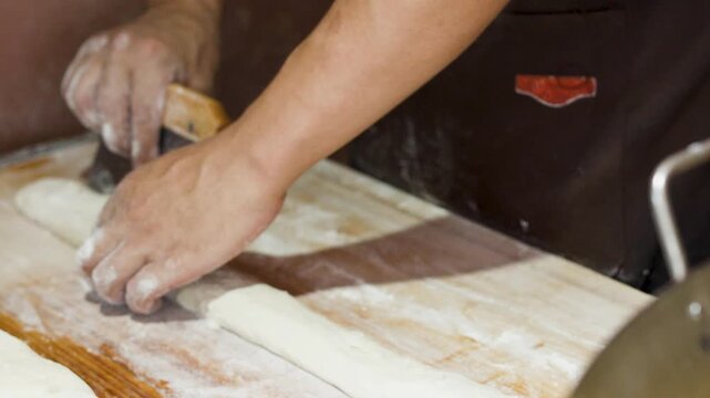 Close Up of Asian Chef Hands Cutting and Rolling Dough