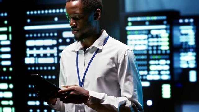African American engineer checks storage infrastructure in a data center, supporting massive datasets, critical workloads and dependable hardware operations during blade server scans.