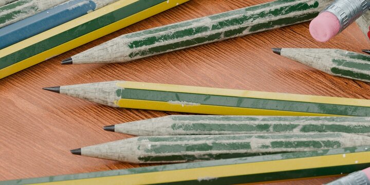 pencils scattered in a pile on a wooden school desk