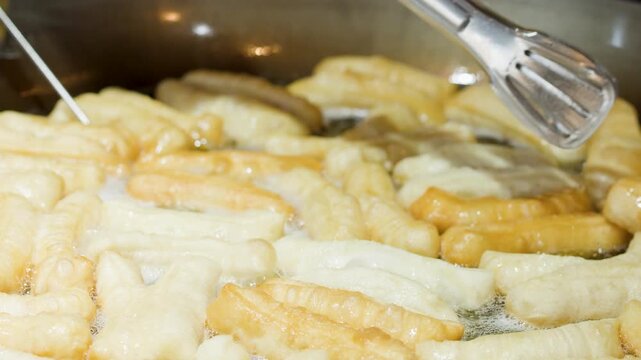 Chef Deep Frying Traditional Chinese Dough Sticks in Hot Oil Wok