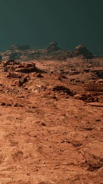 A red and rocky landscape with hills in the background. The ground is dry and dusty, and the sky appears dark and empty. This view captures a unique environment.