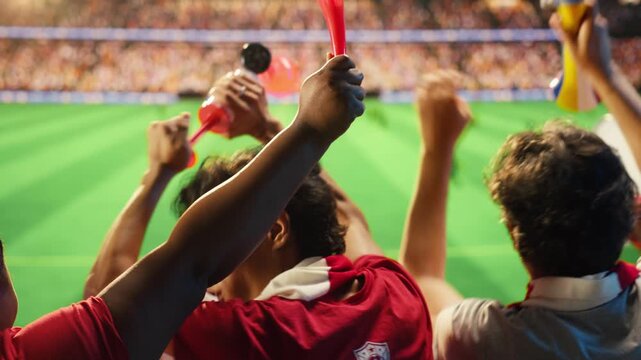 Soccer fans in red shirts react with excitement to goal scored during match for goal celebration, supporter emotion and fan culture content.