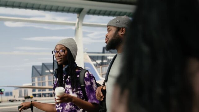 Smiling friends chatting in airport, holding coffee cup, relaxed African American passengers in airport terminal talking, drinking beverage, for lifestyle travel and airport passenger concepts.