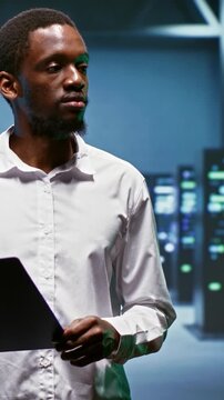 Vertical aspect: Engineer works inside a data center supporting artificial intelligence, machine learning datasets and large scale computing resources.