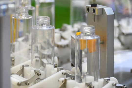 Mass production process of clear plastic bottles moving on an automatic conveyor belt.