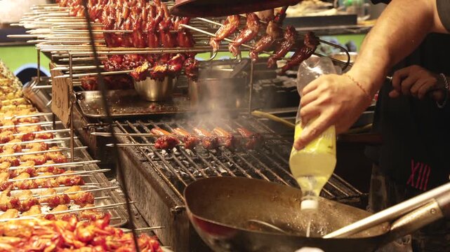 Close up Street Chef hands Grilling Chicken Skewers with Smoking Wok at Night Market Stall