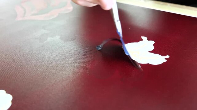 Fine tool applies a small touch up dab of dark red pigment onto a dyed fabric section