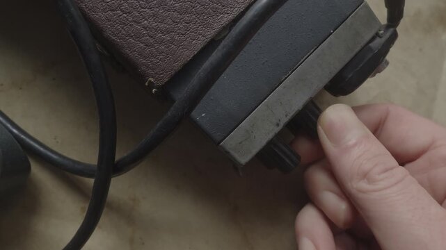 Close-up of fingers tuning a retro two-way radio, conveying covert surveillance, tactical communication, espionage, and police intelligence operations.